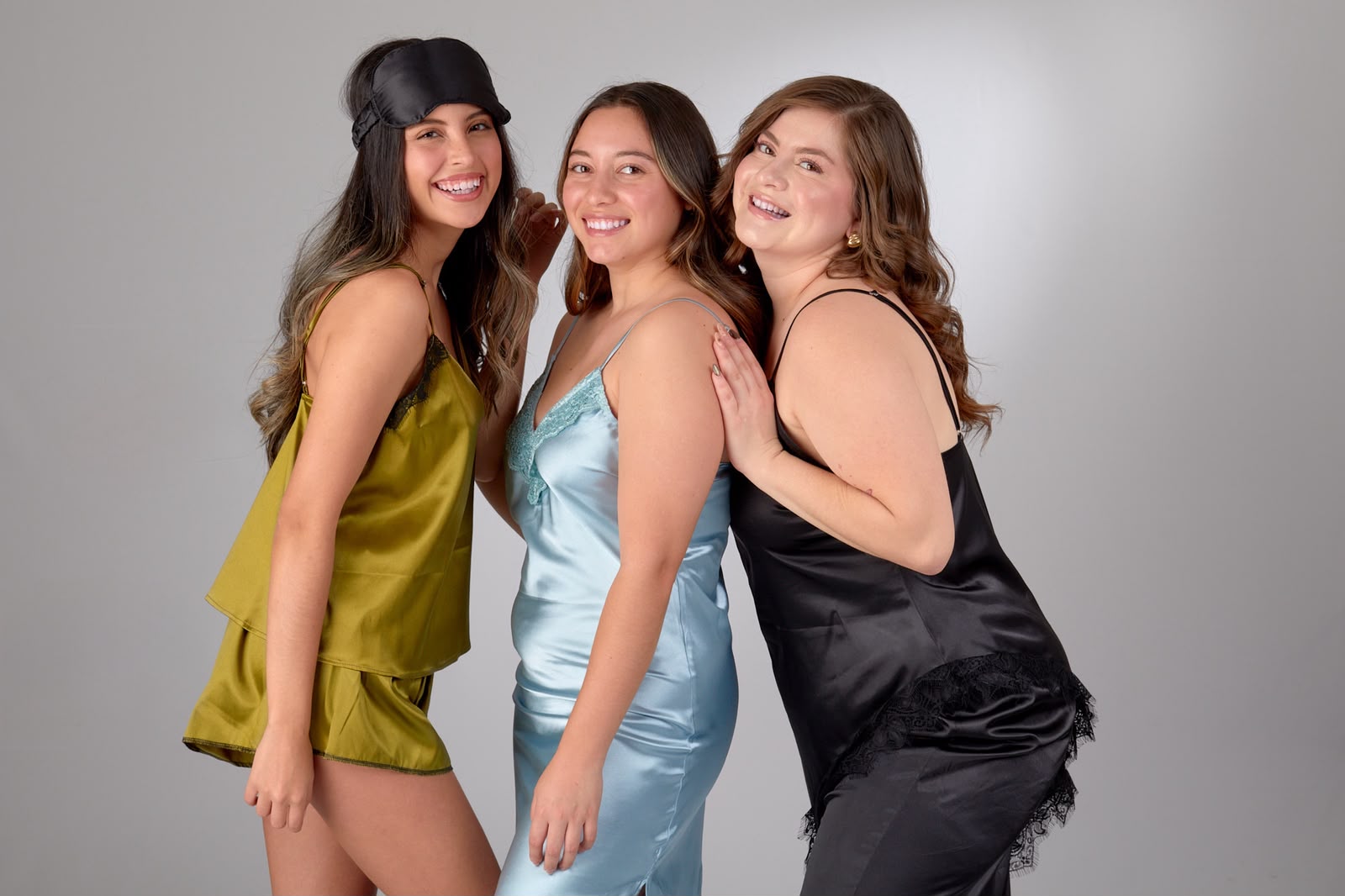 Tres modelos con slips de satén oliva, azul hielo y negro