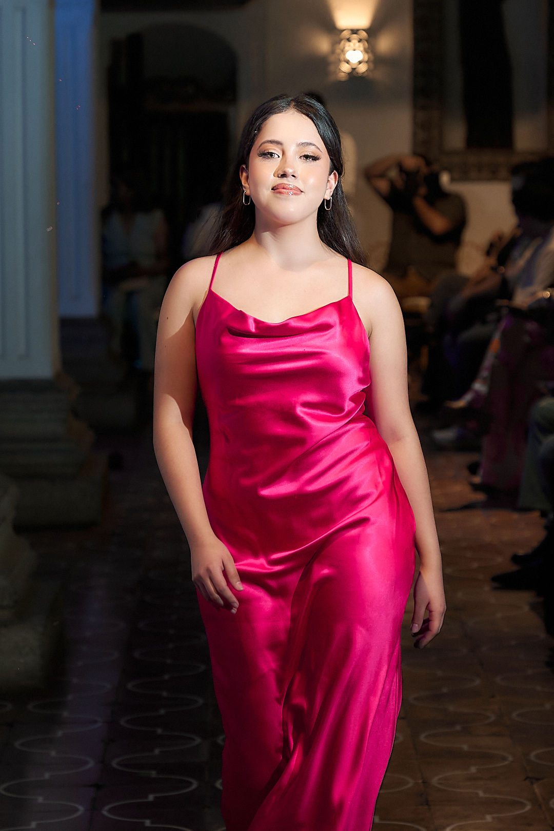 Modelo en la pasarela de Antigua Guatemala con vestido largo de satén fucsia